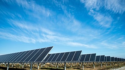 Ground-mounted solar panels beneath a blue sky.