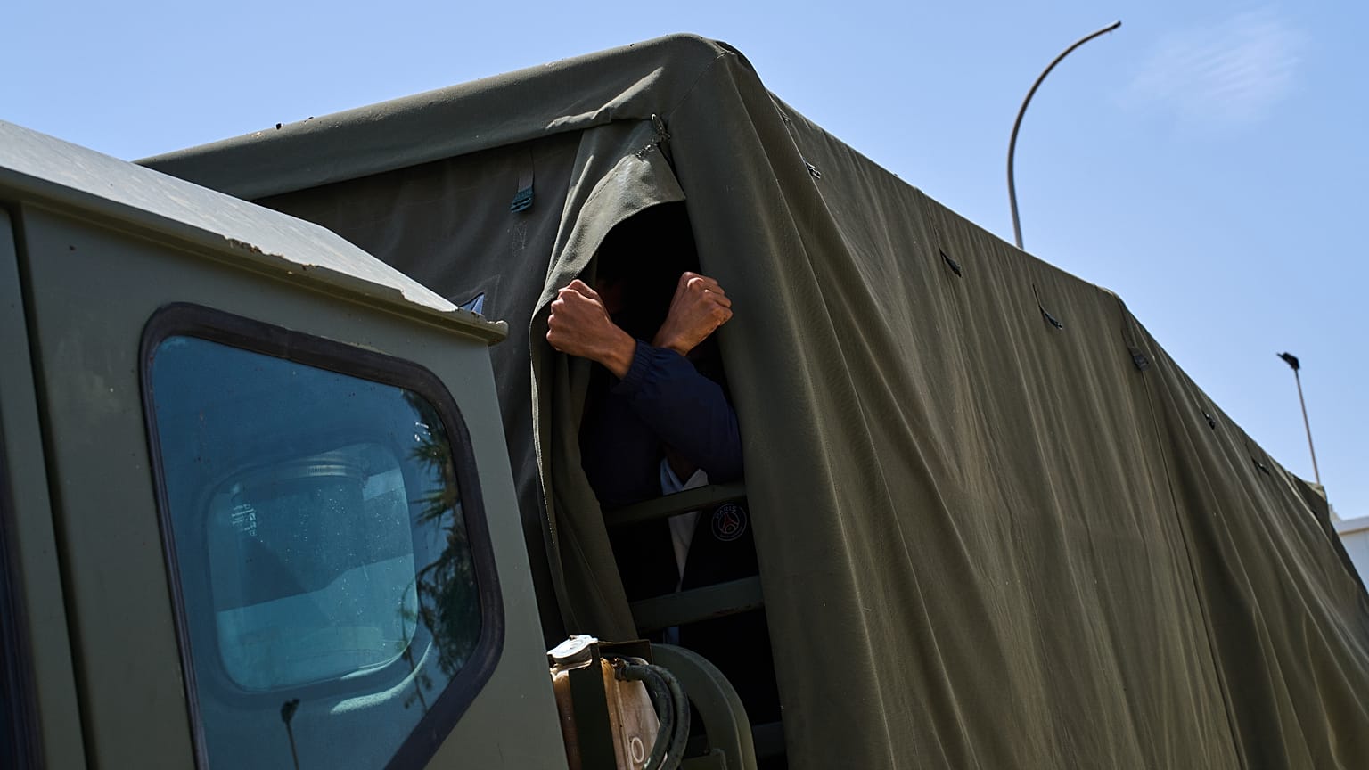 A Moroccan migrant who crossed into Spain gestures from a truck as the army sends him back to Morocco on 3 August 2026.