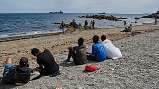 Migrants who crossed into Spain from Morocco gather on a beach in the Spanish enclave of Ceuta, Monday, Aug. 3, 2026.