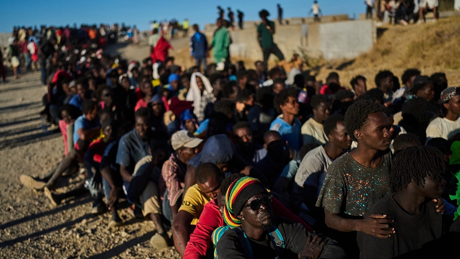Migrants who crossed from Morocco into Spain line up for food distribution on a beach in the Spanish enclave of Ceuta, 3 August, 2026