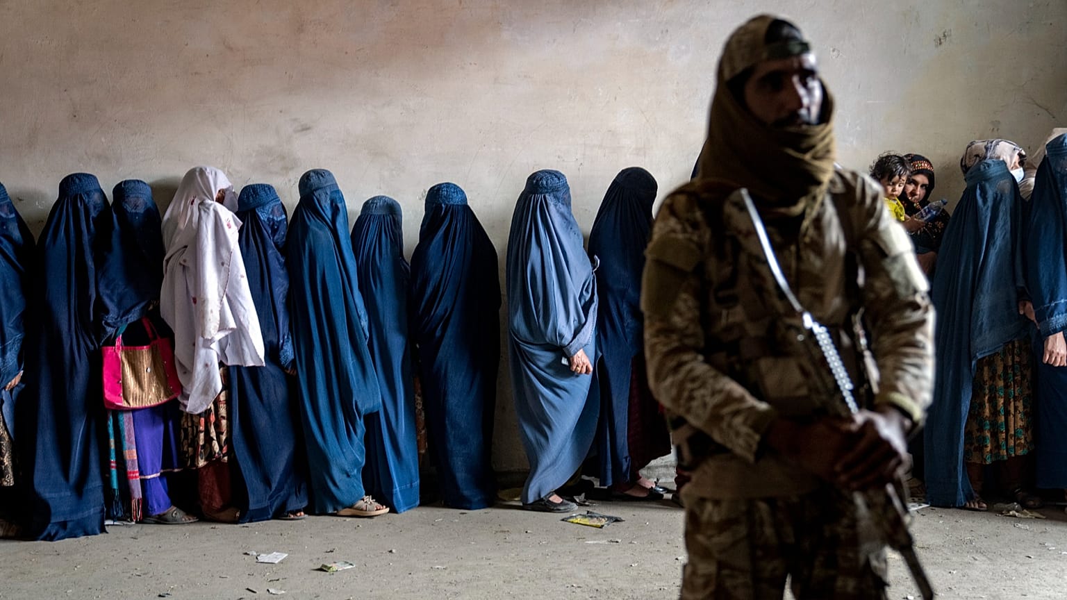FILE - A Taliban fighter stands guard as women wait to receive food rations distributed by a humanitarian aid group, in Kabul, Afghanistan, on 23 May, 2023.