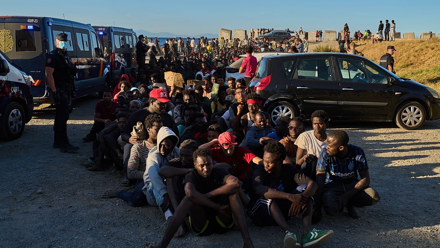 Migrants who crossed from Morocco into Spain queue for food on a beach in the Spanish enclave of Ceuta, Monday, 3 Aug 2026.