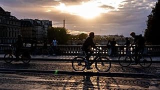 Cyclists ride on a bridge spanning the Seine at sunset on Thursday 28 August 2025 in Paris.