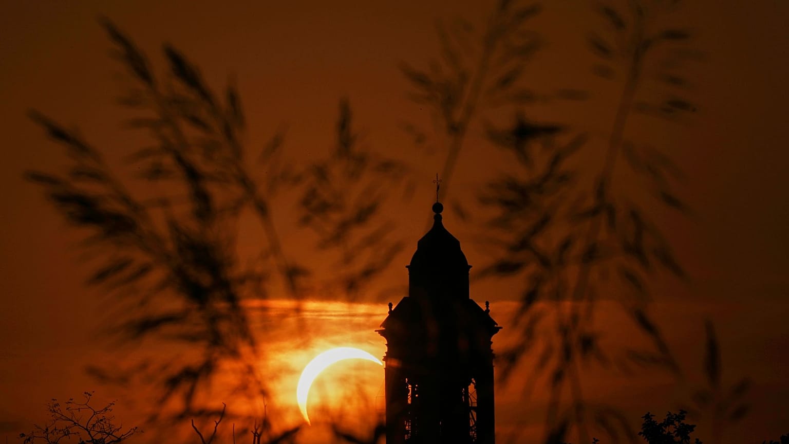 A solar eclipse is seen over a Virgin Maria church in Vidigulfo, near Pavia, northern Italy