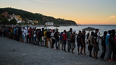 Migrants who crossed from Morocco into Spain line up for food distribution on a beach in the Spanish enclave of Ceuta, Monday, Aug. 3, 2026