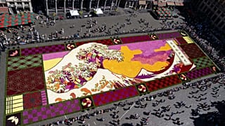 An overview of a giant flower carpet inspired by The Great Wave off Kanagawa by Japanese artist Katsushika Hokusai at the historic Grand Place in Brussels